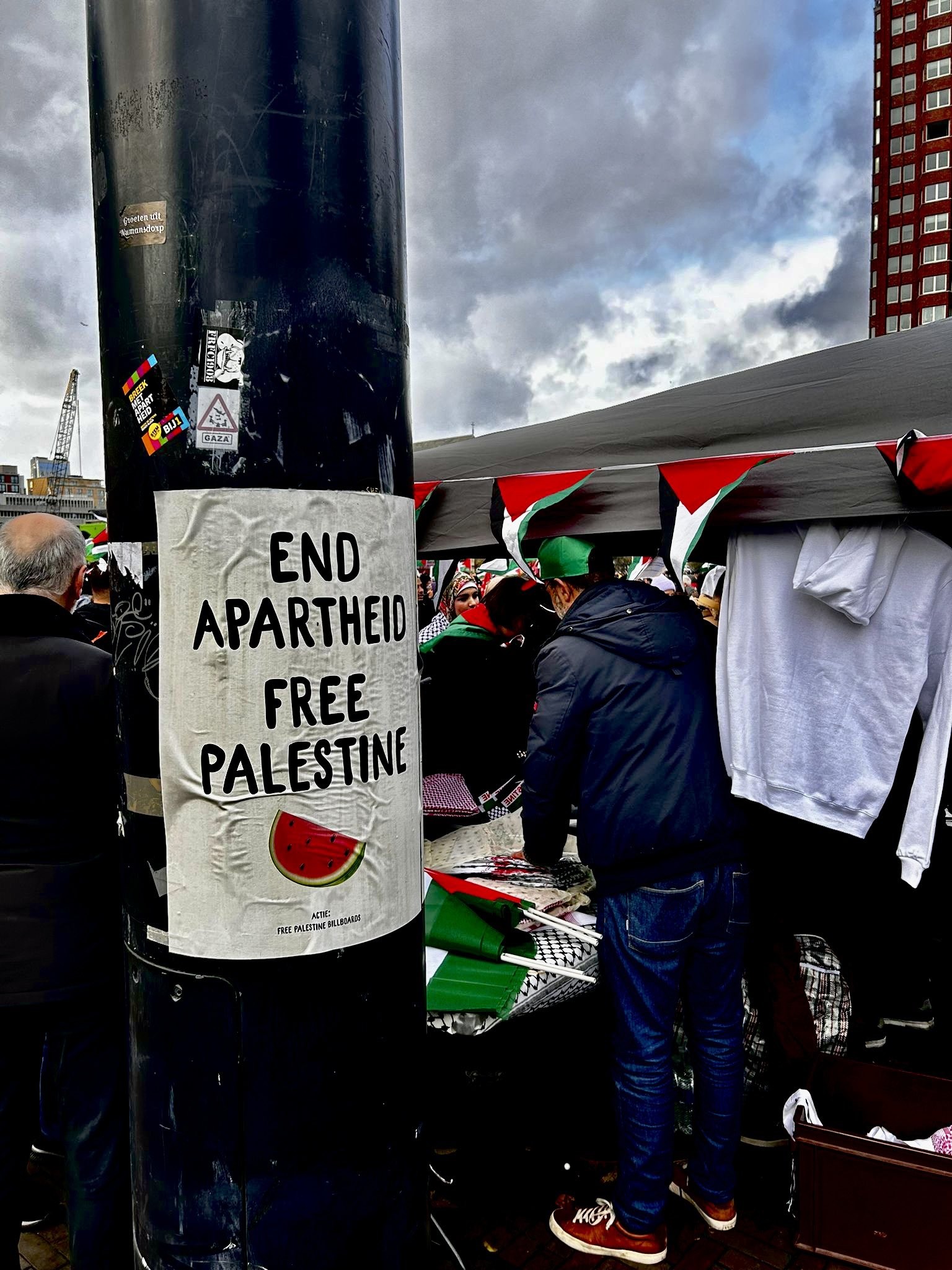Foto van de demonstratie met een poster op een paal met de tekst: 'END APARTHEID, FREE PALESTINE'.